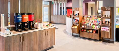 A modern coffee station with multiple dispensers and a snack display.