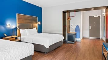 A modern hotel room with two beds, a desk, and a shower area.