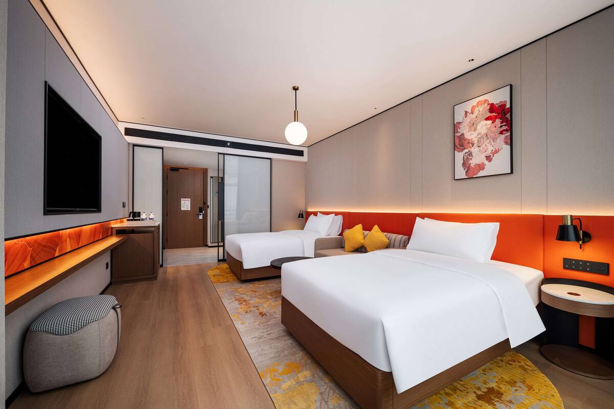 A modern hotel room with a large bed, a desk, and a TV.