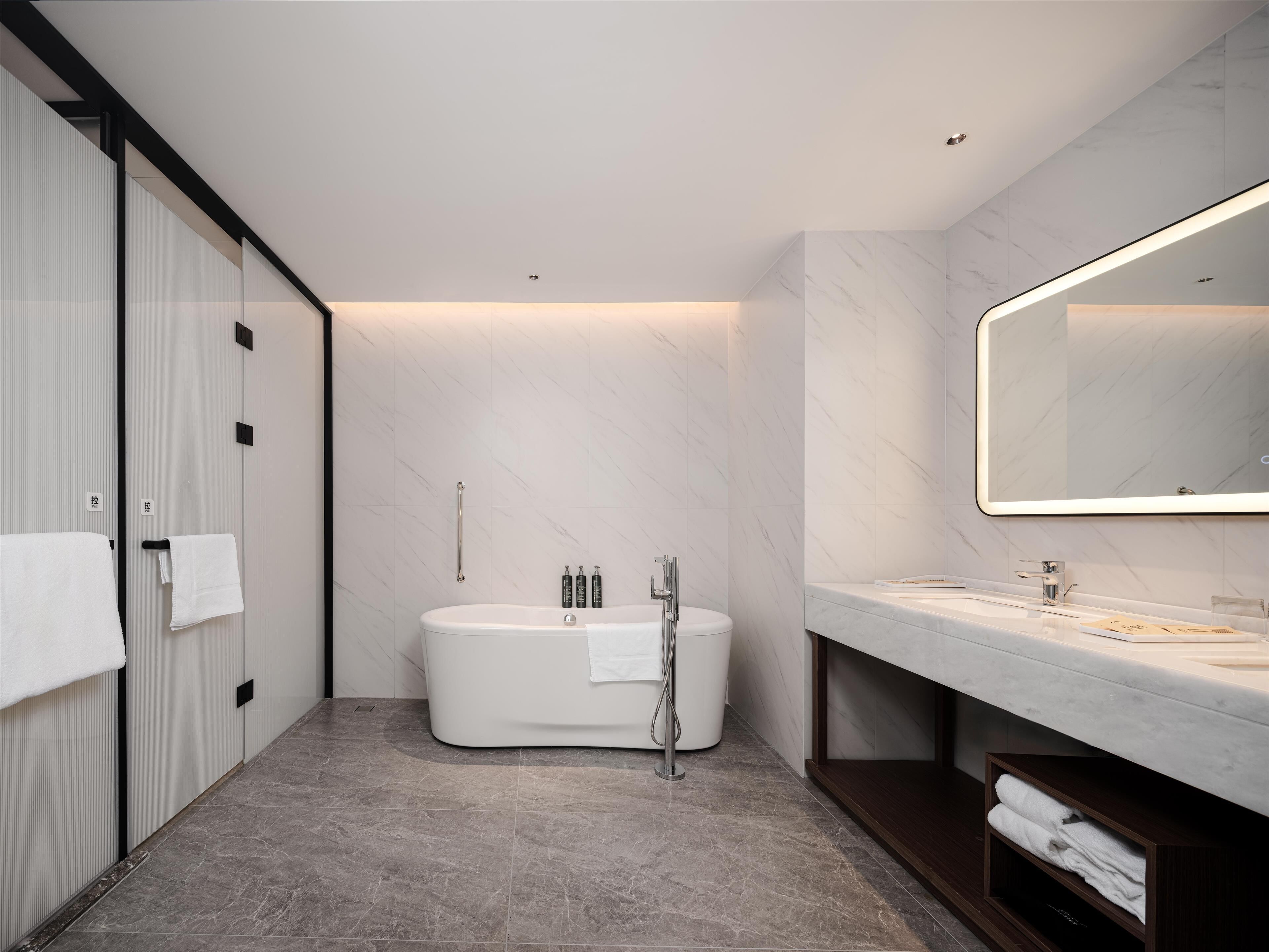 A modern bathroom with a freestanding bathtub, a large mirror, and a vanity with a countertop.