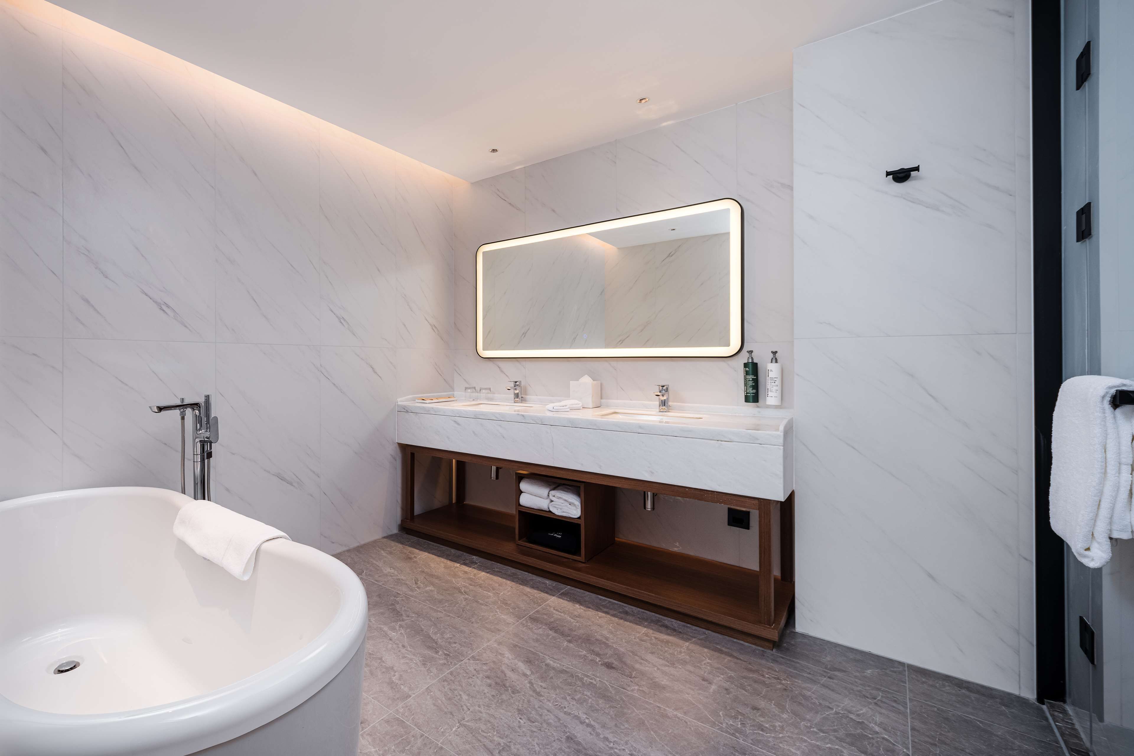A modern bathroom with a freestanding bathtub, a large mirror, and a vanity with two sinks.