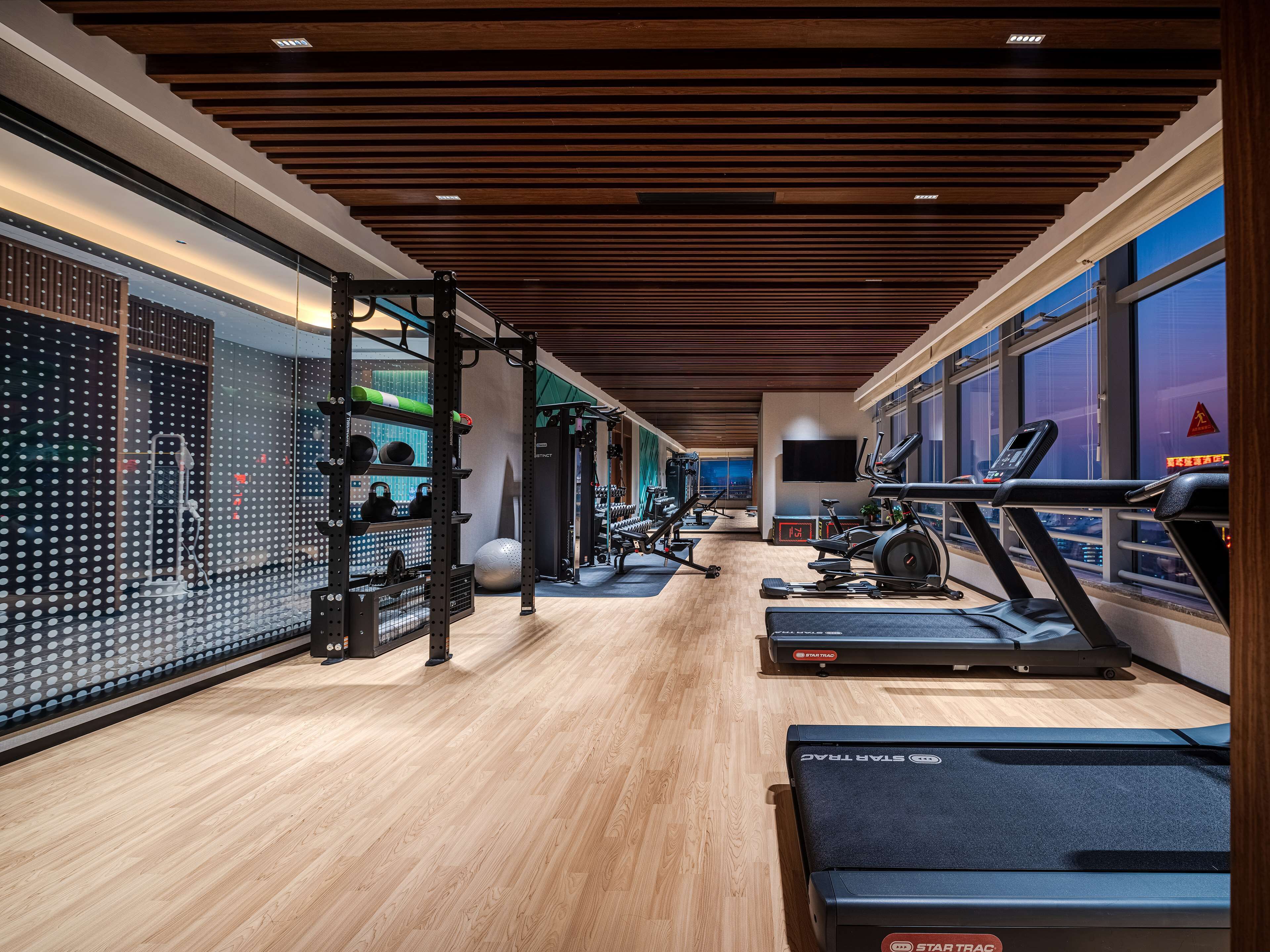 Ein modernes Fitnessstudio mit Laufbändern, Krafttrainingsgeräten und einer Übereck-Trainingszone.