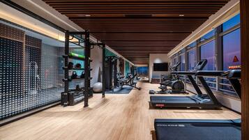 Ein modernes Fitnessstudio mit Laufbändern, Krafttrainingsgeräten und einer Übereck-Trainingszone.
