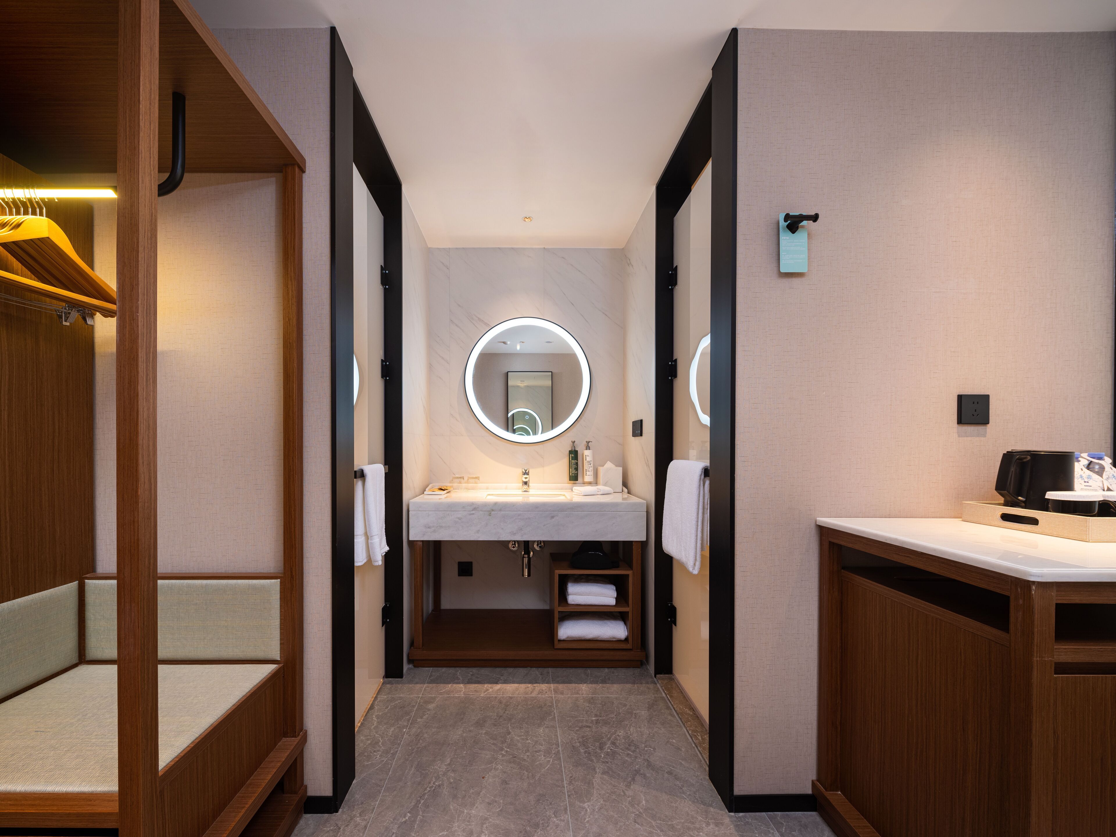 A modern bathroom with a vanity, a round mirror, and a towel rack.