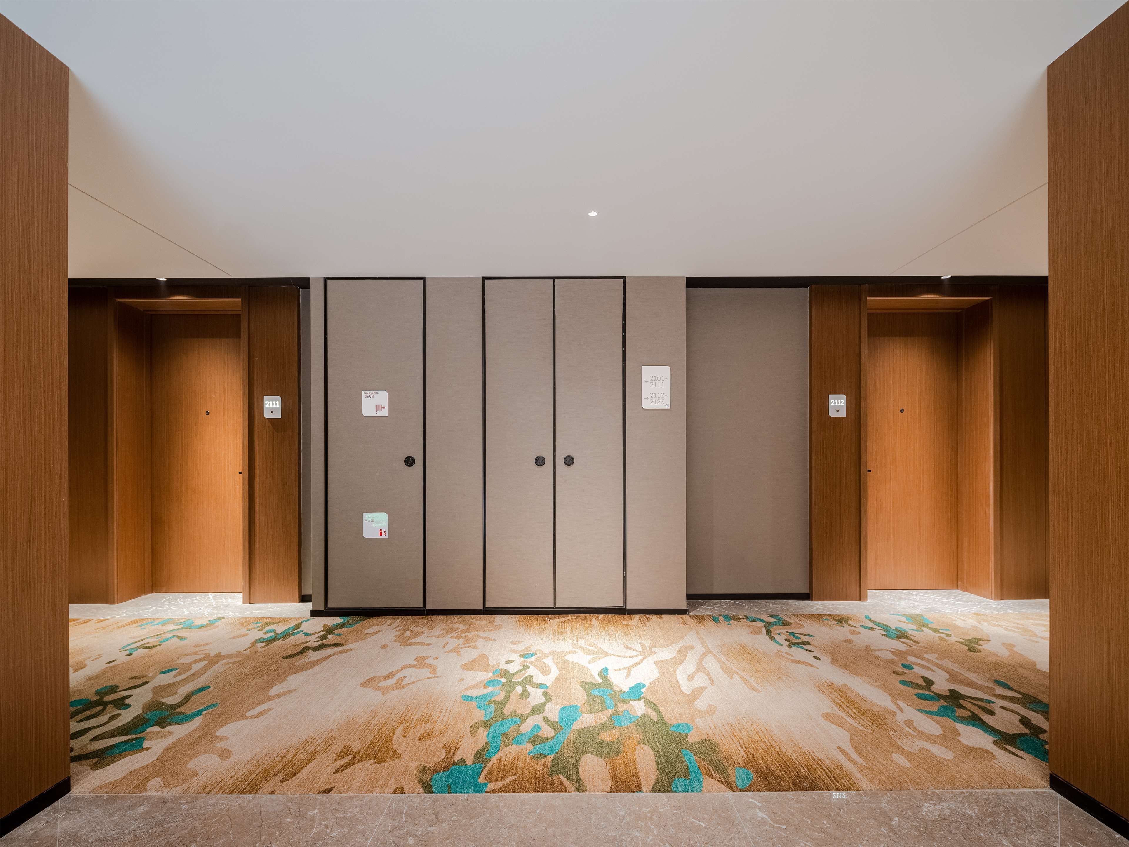 Habitación de hotel con un armario grande, alfombra estampada y suelo de mármol.