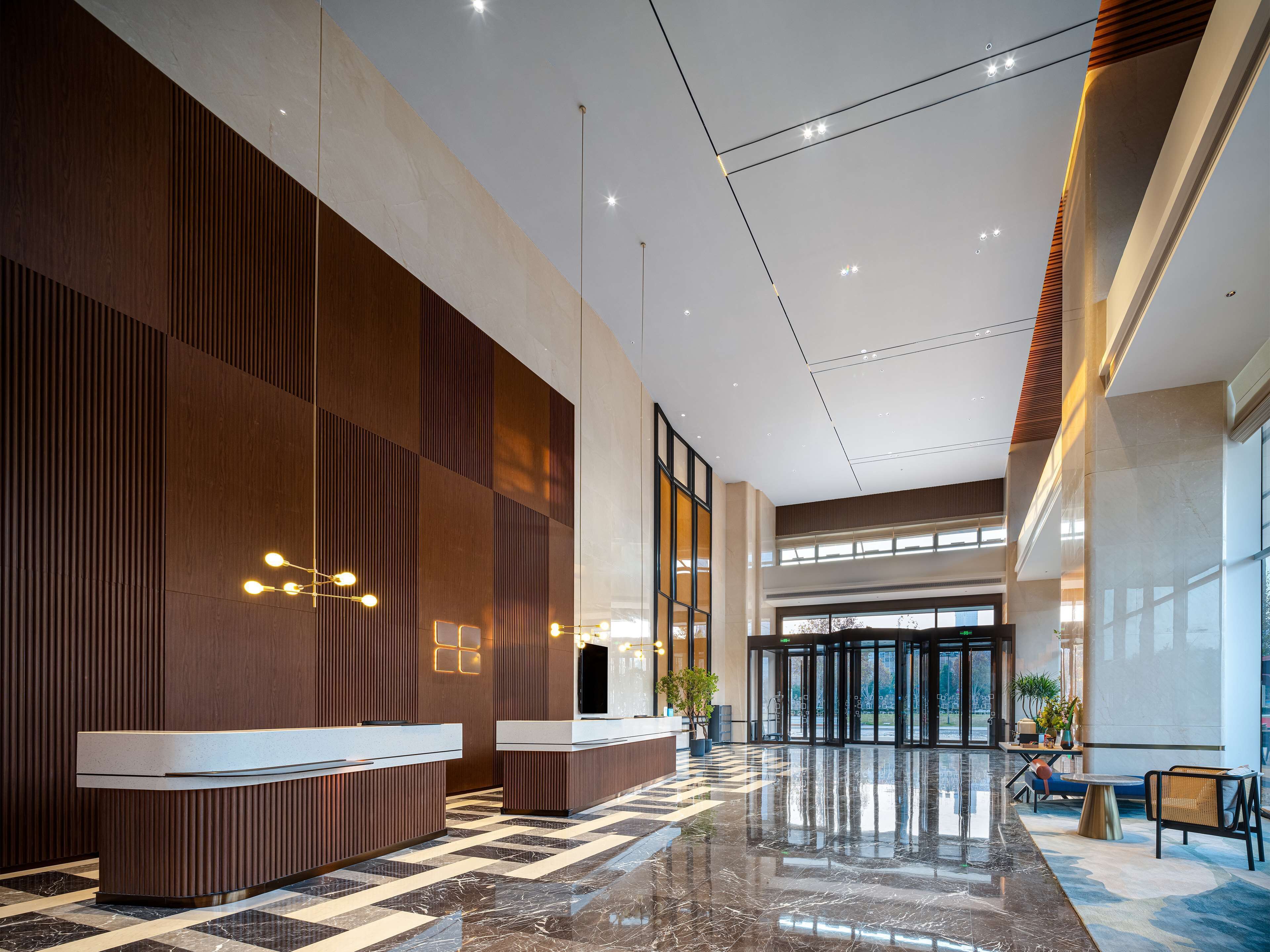 A spacious lobby with a check-in counter, large windows, and a polished marble floor.