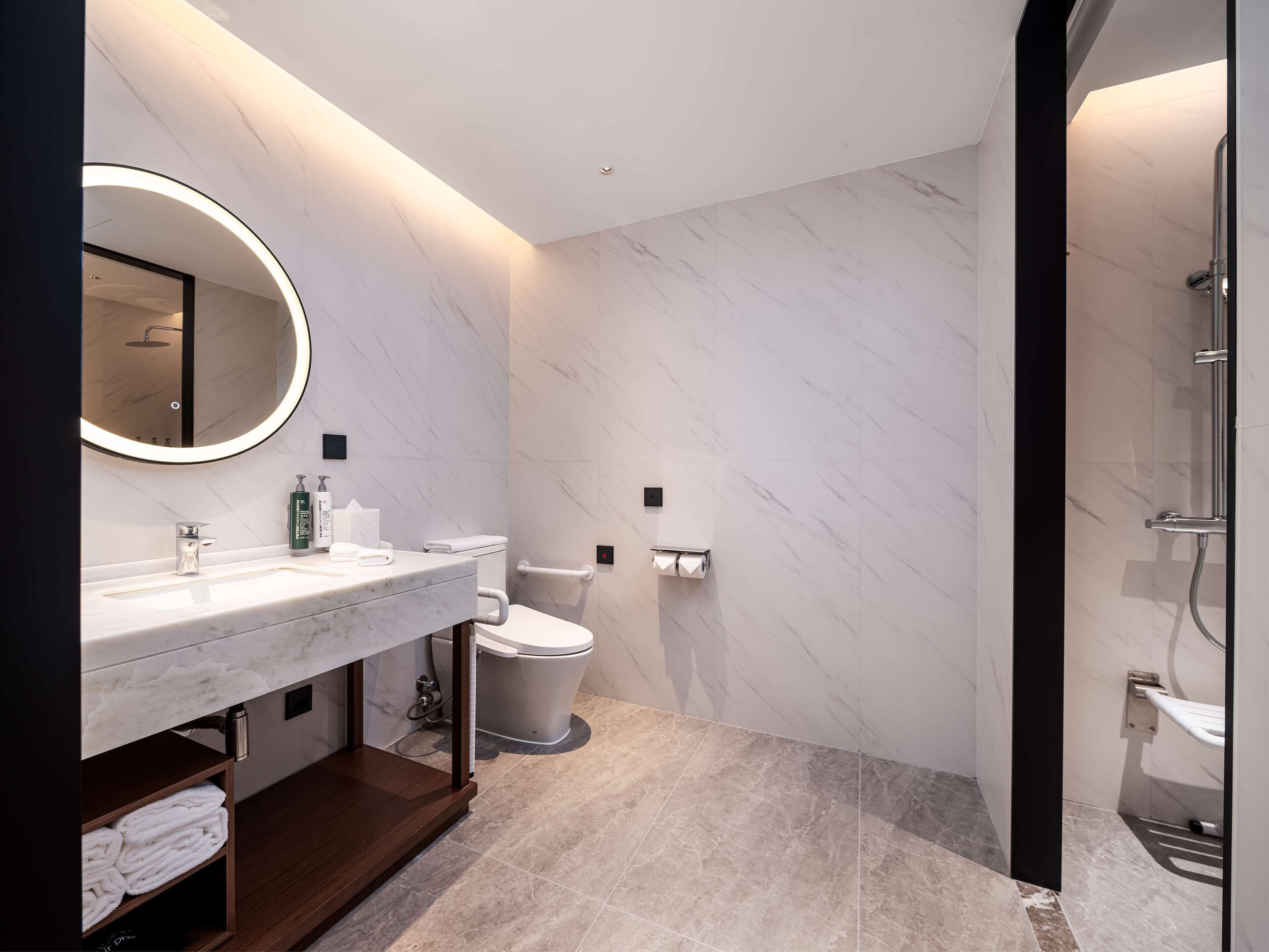 A modern bathroom with a marble vanity, a toilet, and a shower area.