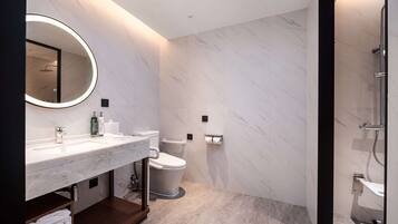 A modern bathroom with a marble vanity, a toilet, and a shower area.