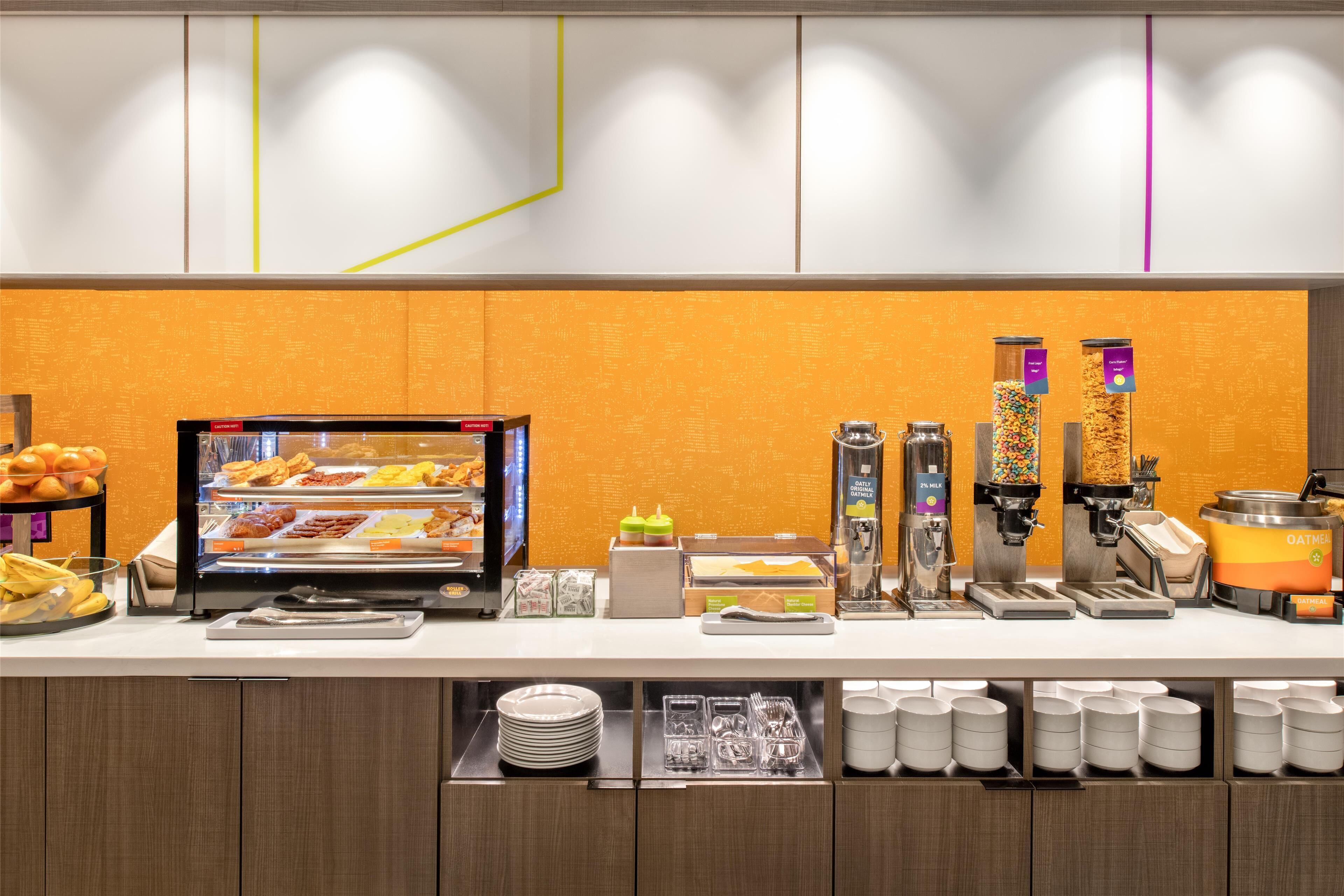 A breakfast buffet with various food items, a coffee machine, and a milk dispenser.