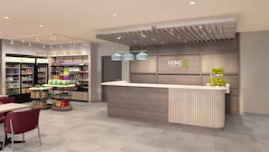 A modern hotel lobby with a reception desk, a seating area, and a variety of retail displays. - Home2 Suites By Hilton Woodland Sacramento (Woodland)