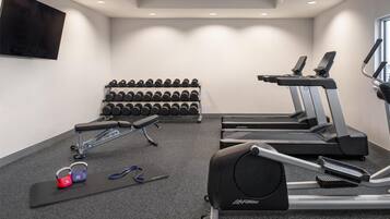 A gym with treadmills, dumbbells, and a bench.