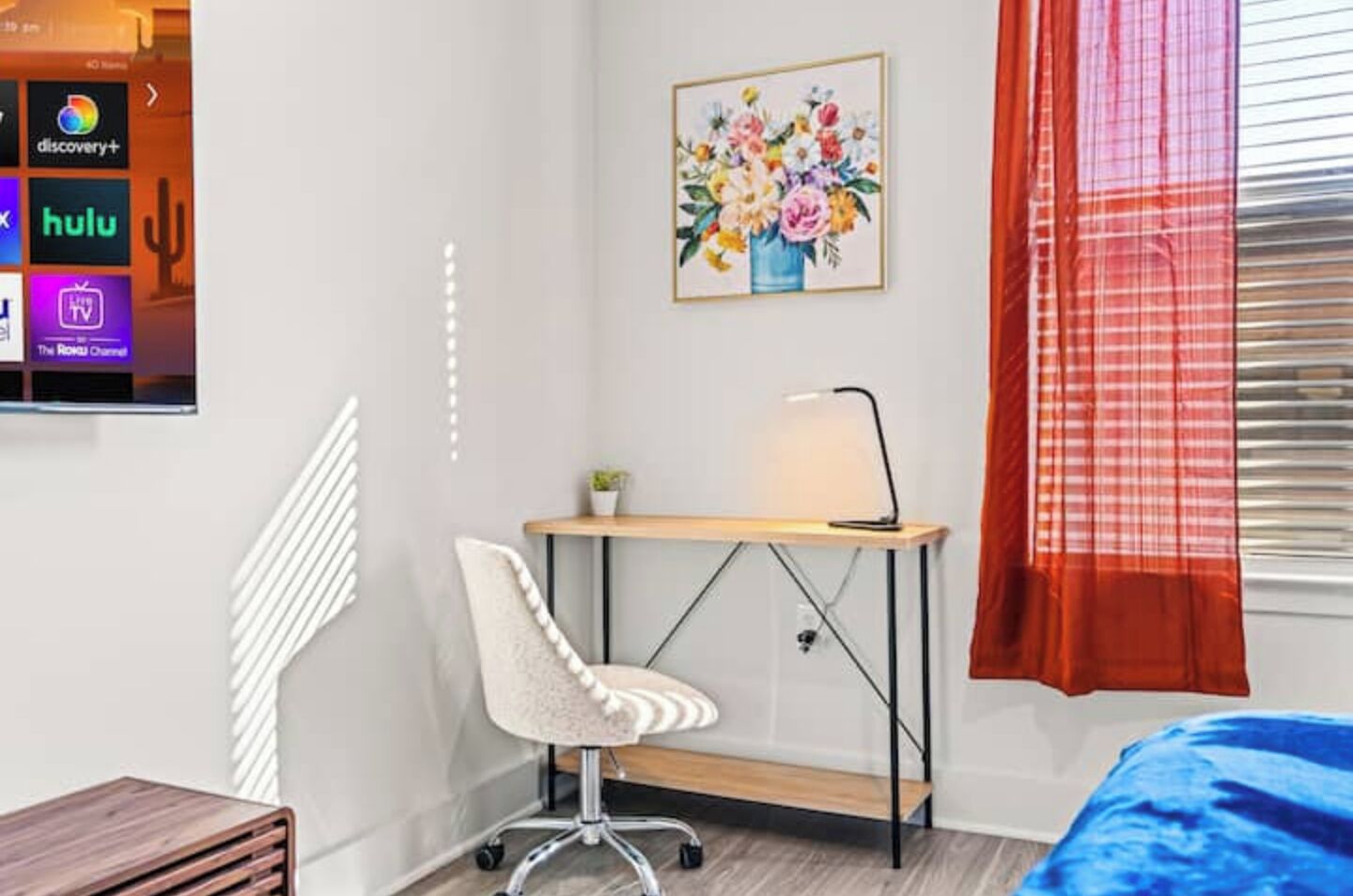 Ein Schlafzimmer mit Schreibtisch, Stuhl und einem Bild an der Wand.