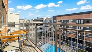 Een dakterras met een zwembad, omheind door een metalen hek, met uitzicht op een stadslandschap.