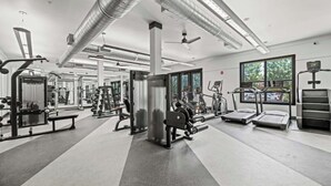 Un gimnasio moderno con diversos equipos de ejercicio, ventanas amplias y un diseño limpio y espacioso.