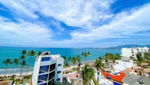 A coastal hotel with a view of the ocean and palm trees. - Luxury Apartment 50m from Beach in Bucerías w/ Balcony & Rooftop Garden (Bucerías)