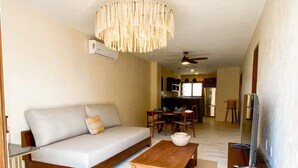 A modern living room with a sofa, coffee table, and TV stand. - Luxury Apartment 50m from Beach in Bucerías w/ Balcony & Rooftop Garden (Bucerías)