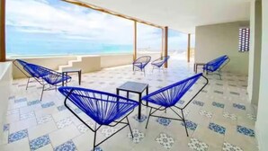 A terrace with blue chairs and a table, overlooking a beach. - Luxury Apartment 50m from Beach in Bucerías w/ Balcony & Rooftop Garden (Bucerías)