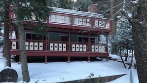 Ein zweistöckiges Gebäude mit roter Fassade und weißer Verzierung, umgeben von schneebedeckten Bäumen.