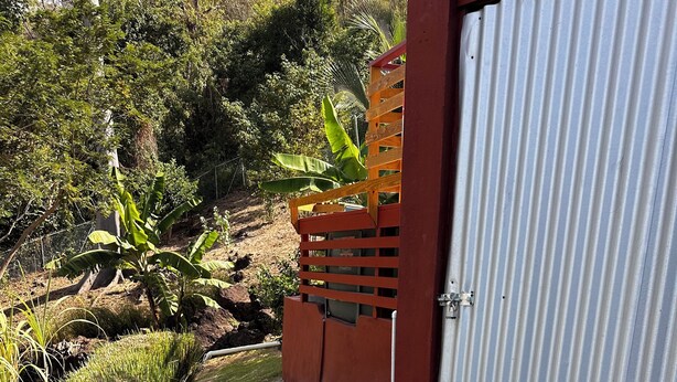 Un sendero que lleva a un edificio con una puerta de metal corrugado y un banco de madera.