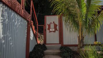 Una entrada con portón, un letrero con forma de estrella, una escalera de metal y una palmera.