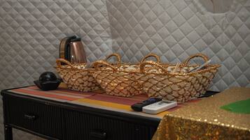 A bed with a quilted headboard, a bedside table with a remote control, a black lamp, and a decorative basket.
