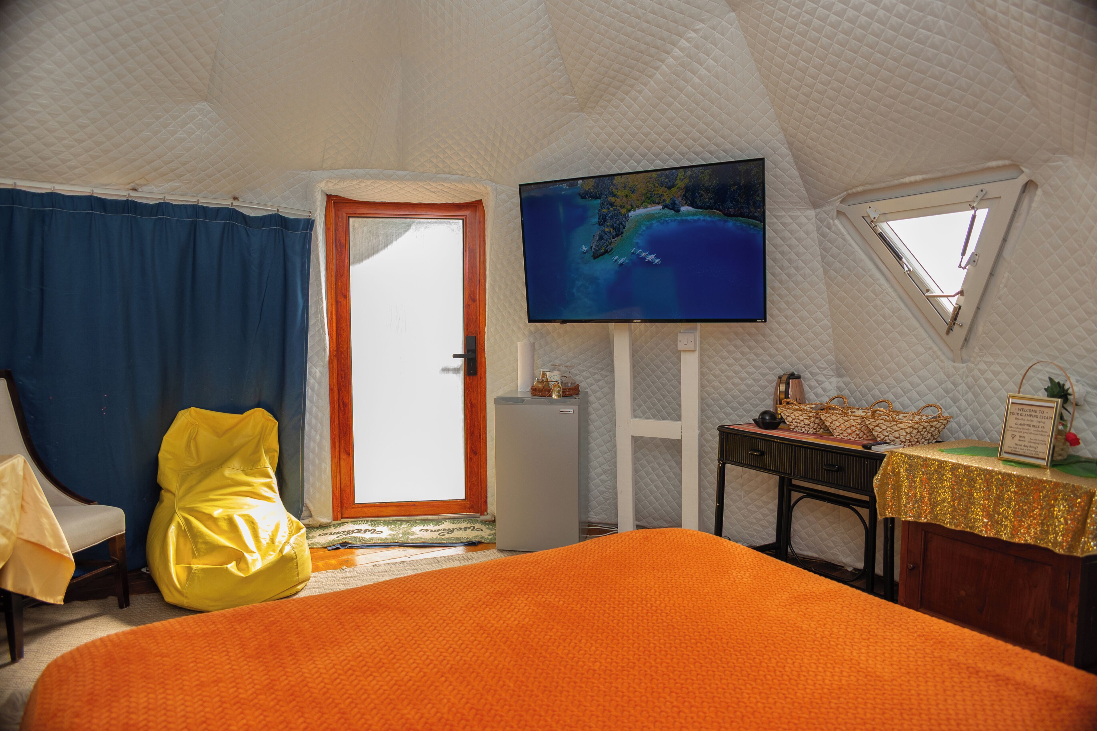 A room with a bed, a chair, a television, a desk, and a window.