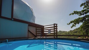 Una piscina con muelle de madera, zona cubierta y vista a la vegetación.