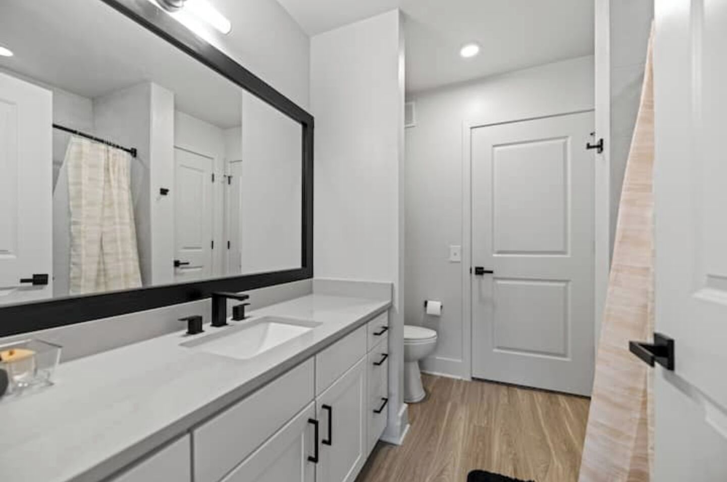 Un bagno moderno con uno specchio grande, due lavabi, un water e una tenda da doccia.