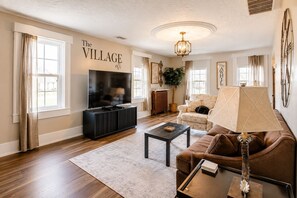 A living room with a TV, sofa, coffee table, and a wall with 'The Village off' text.
