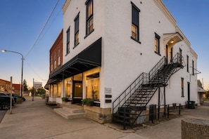 Un edificio blanco con toldo negro, una escalera y un letrero que dice 'VILLAGE Pizza Place'.