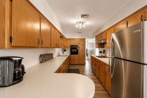 A modern kitchen with wooden cabinets, a stainless steel refrigerator, and a coffee maker.