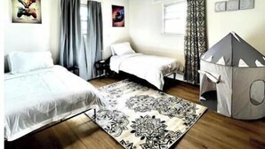 A room with two beds, a play tent, and a patterned rug.