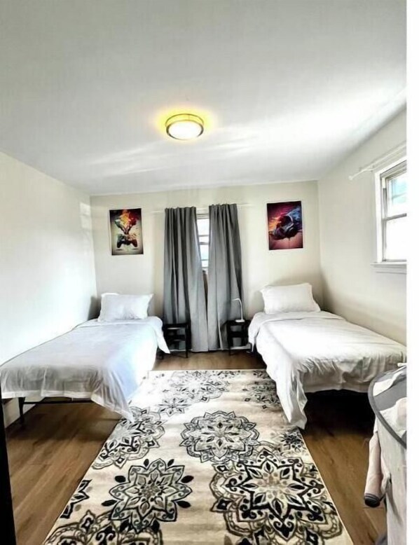 A room with two beds, a patterned rug, and two wall art pieces. - New Modern Ranch Close to it All (Piscataway)