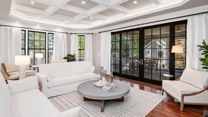 A spacious living room with a white sofa, a round coffee table, and a large sliding glass door leading to an outdoor area. - The Wren + Nest | Main & Guest House | Sleeps 10 (Columbia)