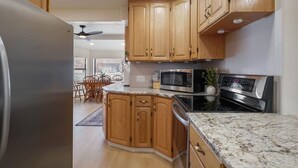 A kitchen with wooden cabinets, a granite countertop, a refrigerator, a microwave, and an oven. - Family-Friendly 4BR Provo Home Close to Provo Airport (Provo)