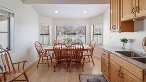 A kitchen with wooden cabinets, a dining table with chairs, and a window with blinds. - Family-Friendly 4BR Provo Home Close to Provo Airport (Provo)