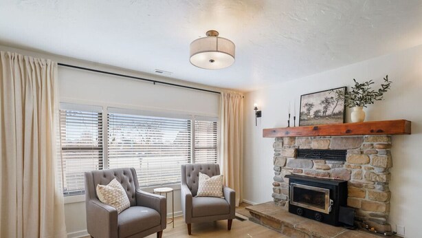 A living room with two armchairs, a stone fireplace, and a ceiling light fixture. - Family-Friendly 4BR Provo Home Close to Provo Airport (Provo)