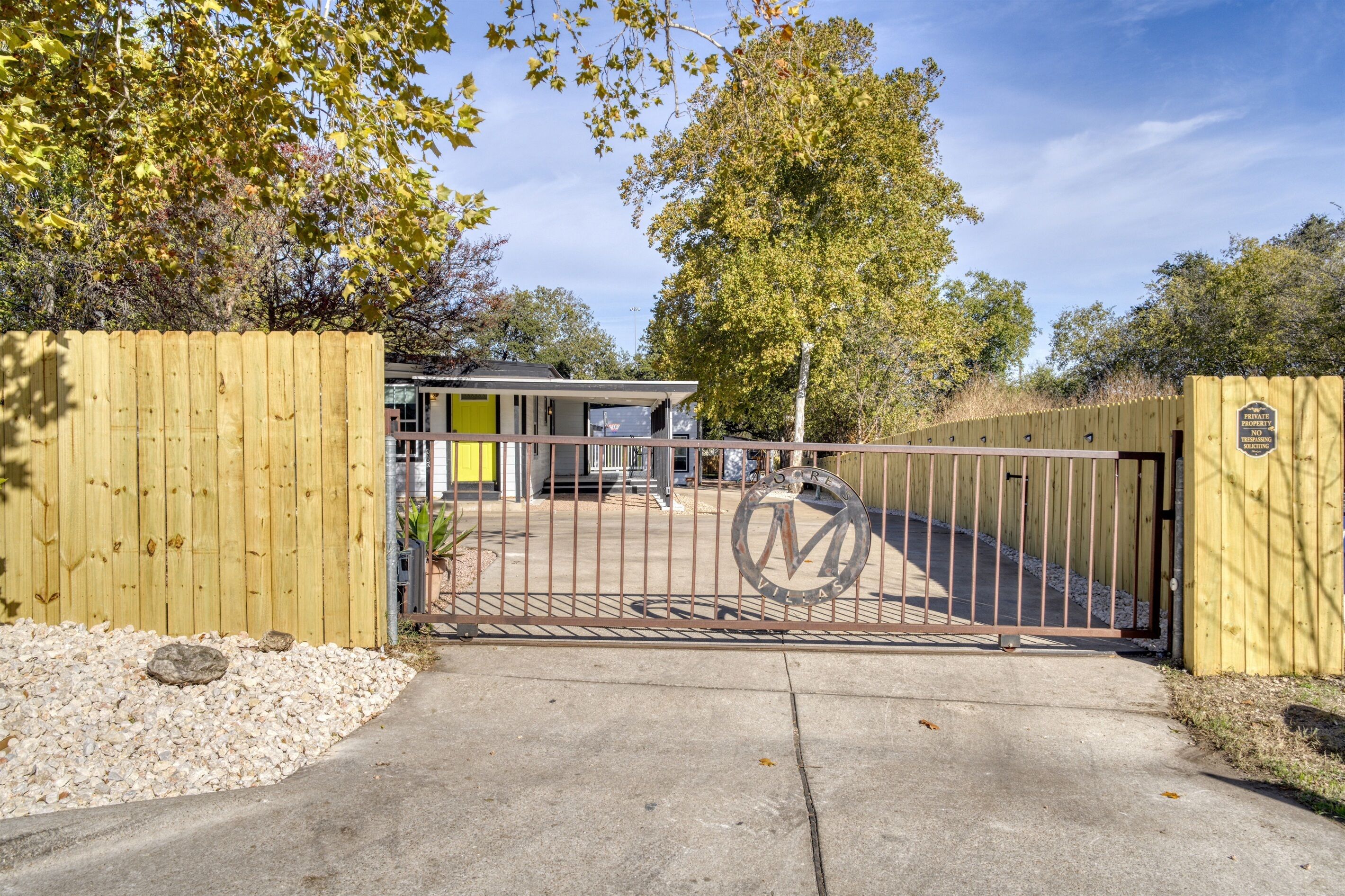 A gated entrance to a property with a wooden fence and a metal gate.