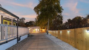 Un chemin menant à un bâtiment entouré d’une clôture en bois et doté d’un mur blanc.