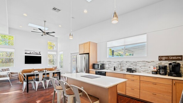 A modern kitchen with a central island, wooden cabinets, a built-in microwave, and a coffee station. - Austin Gated Oasis | 4BR | Sleeps 8 | Fire Pit (Austin)