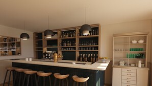 Eine moderne Küche mit einer zentralen Kochinsel, Barhocker und eingebauten Regalen mit verschiedenen Flaschen und Gläsern.