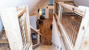 A wooden staircase leading to a lofted area with a view of a forested landscape. - Saddle Tree - Etowah River - Firepit - New Build (Dahlonega)