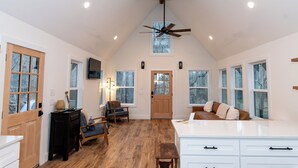 A spacious kitchen with wooden flooring, a ceiling fan, and large windows. - Saddle Tree - Etowah River - Firepit - New Build (Dahlonega)