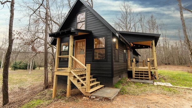 A cabin with a wooden staircase, a porch, and a view of the surrounding forest. - Saddle Tree - Etowah River - Firepit - New Build (Dahlonega)