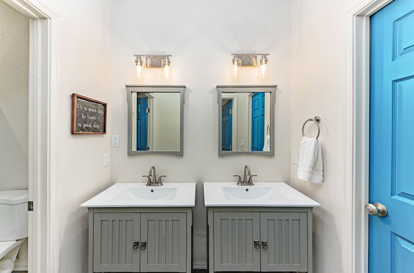 Un baño con dos lavamanos, dos espejos y una puerta azul.