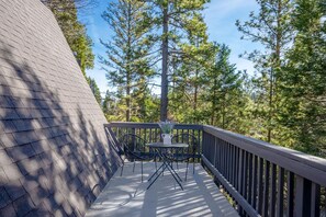 Une terrasse en bois avec une table et des chaises, entourée d’arbres.