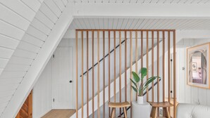 A modern interior with a wooden slat partition, a staircase, and a seating area with a potted plant. - A-Frame + Indoor Sauna & Hot Tub · Lake Arrowhead (Lake Arrowhead)