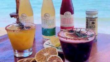 A table with three bottles of kombucha and a large glass of a dark beverage, surrounded by dried citrus slices.