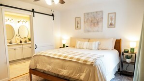 Een slaapkamer met een bed, nachtkastjes, een dressoir en een spiegel.