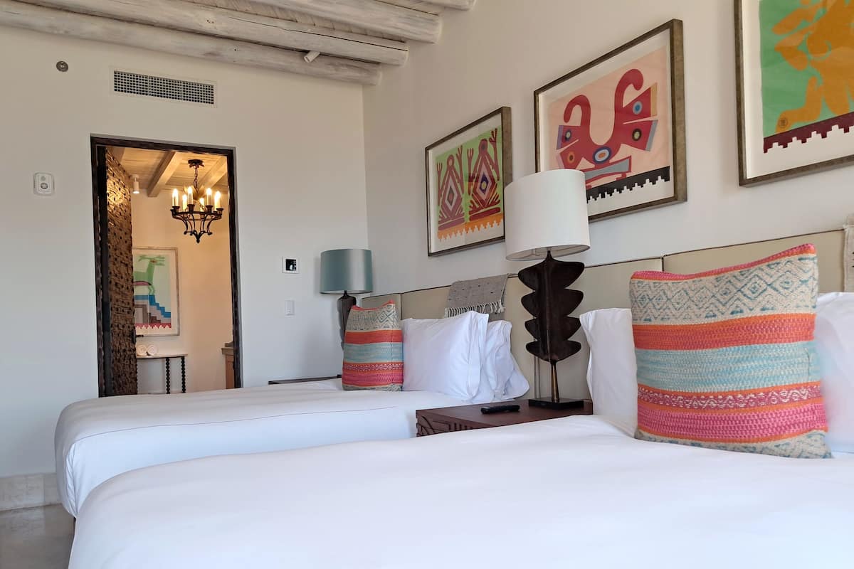 Una habitación de hotel con una cama, una mesita de noche, una lámpara y obras de arte en las paredes.